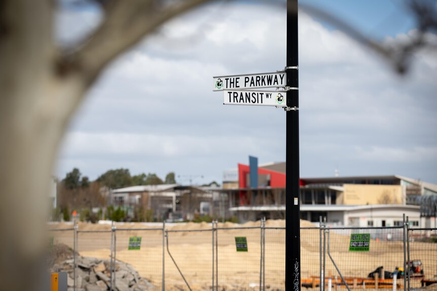 A road sign saying Transit Way in front of a sandy construction site.