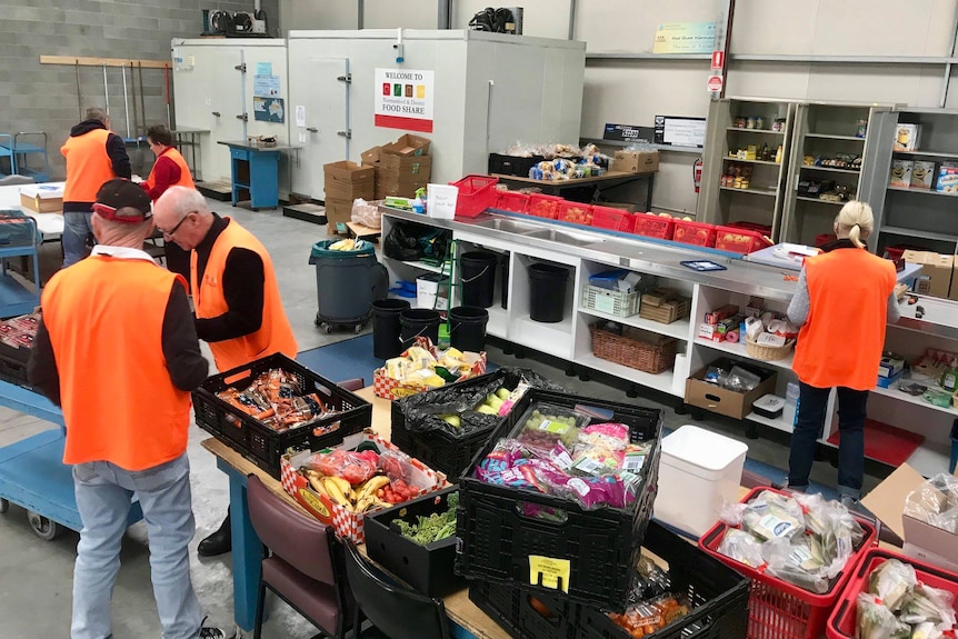 A warehouse with volunteers in high vis vests working on grocery food 