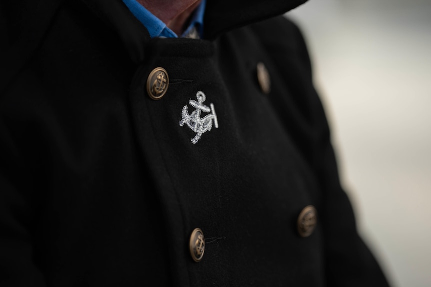 A man's dark blue jacket with a silver badge