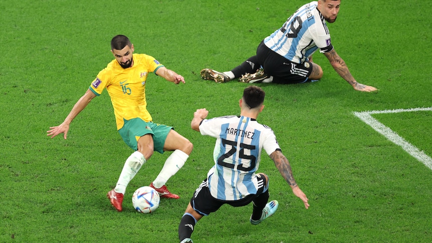 Aziz Behich is about to kick the ball as Martinez moves to stop him and Otamendi watches on his knees behind.
