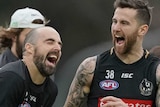 Steele Sidebottom, holing a footy, and Jeremy Howe laugh together while running at training