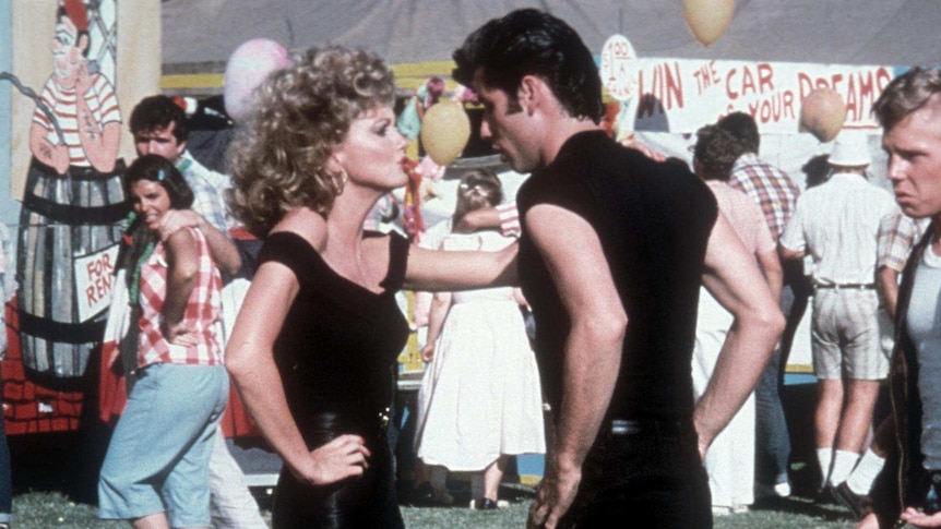 Olivia Newton-John and John Travolta dancing in a scene from Grease. Both are wearing black.