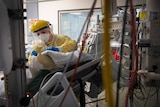 A nurse in PPE works with a patient inside the Intensive Care Unit