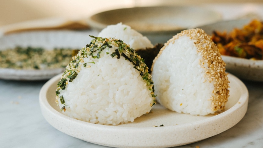 Three onigiri rice balls on a plate with various toppings, made by Hetty Lui McKinnon