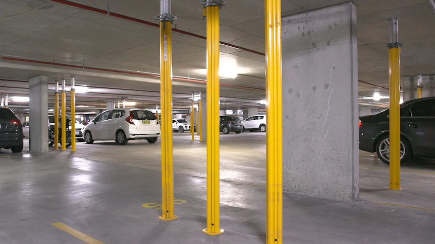 A car park with yellow metal poles running from the floor to the ceiling.