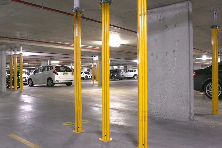 A car park with yellow metal poles running from the floor to the ceiling.