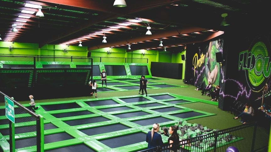 A lime green well lit trampoline park, blaclk trampolines on the ground and walls