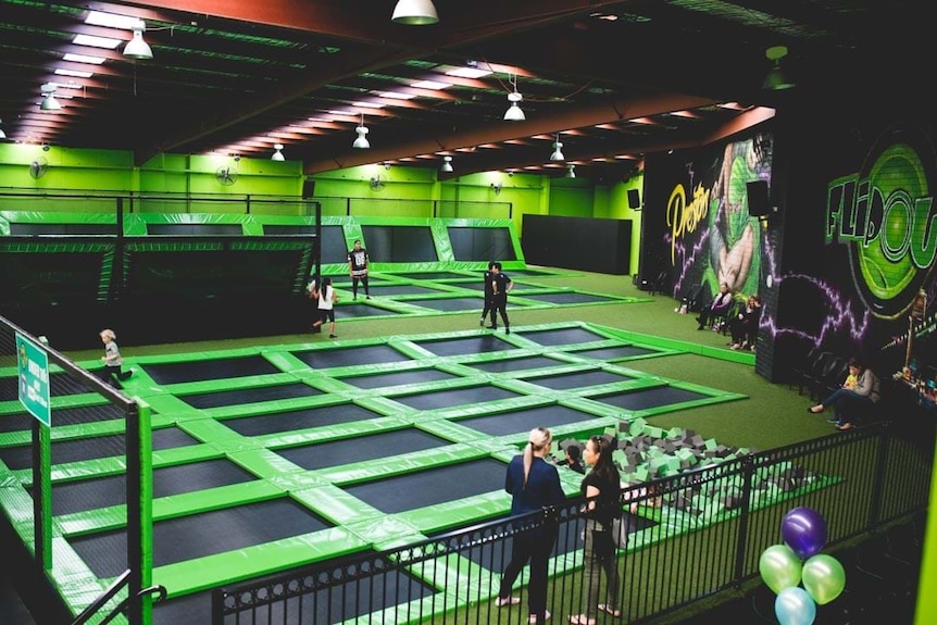 A lime green well lit trampoline park, blaclk trampolines on the ground and walls