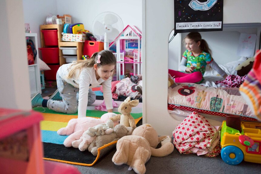 Two girls play with toys in their bedroom.