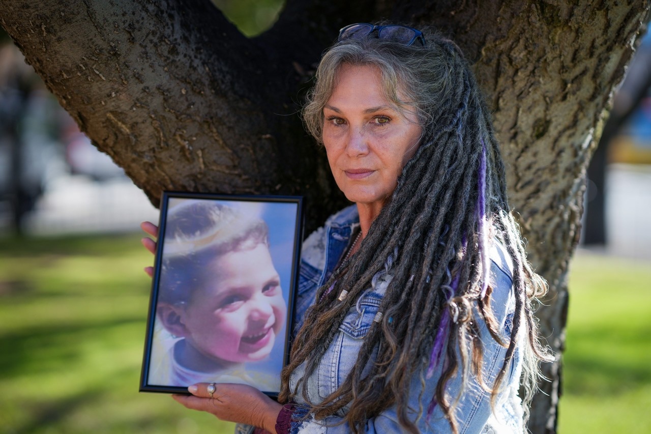 Belinda Valentine looks at the camera as she holds a framed photo of her young granddaughter Chloe Valentine who died in 2012