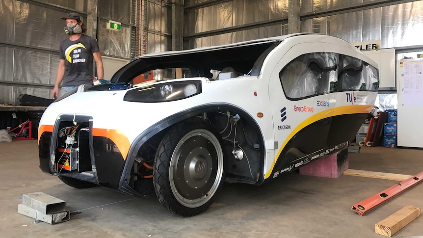 Solar car in a warehouse without a windscreen and with bits missing from its front.