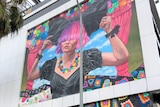 A mural of a woman with pink and purple hair painted on a wall