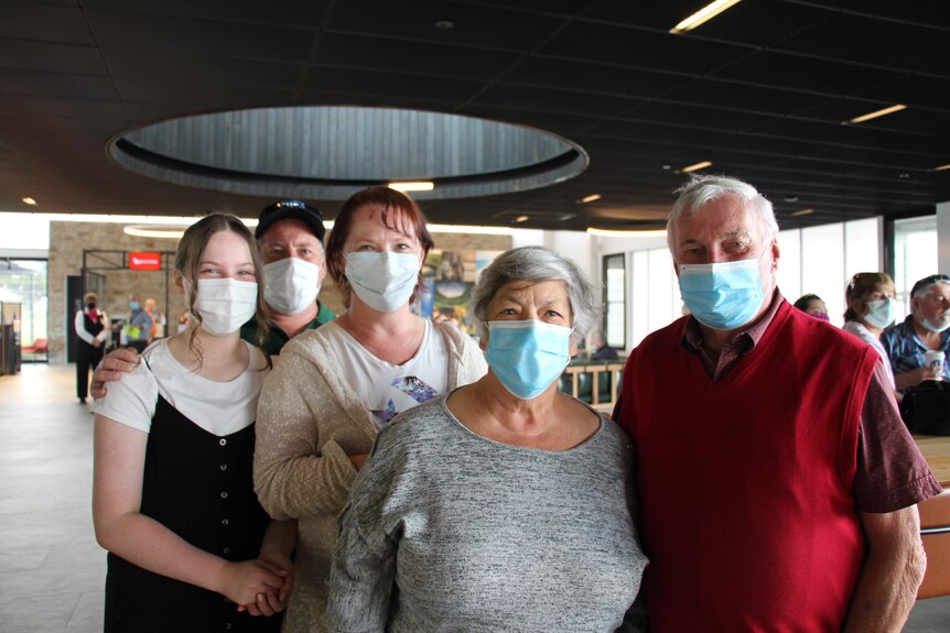 Five people stand looking at the camera wearing masks