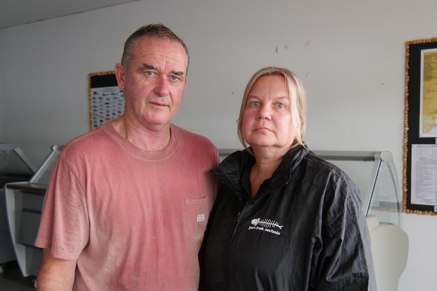 A middle-aged man and woman looking sad in their store. 