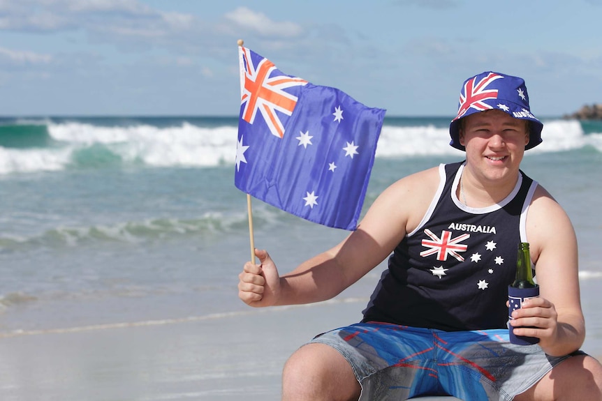 Australian man on the beach with Aussie flags celebrating Australia Day