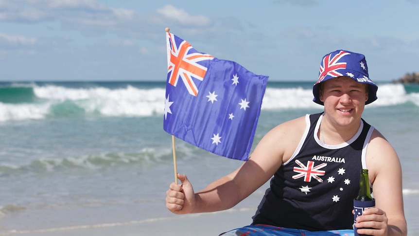 Australian man on the beach with Aussie flags celebrating Australia Day