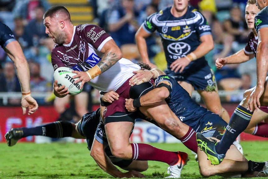 Curtis Sironen has two Cowboys players tackling him by the waste as he tries to force his body towards the tryline.