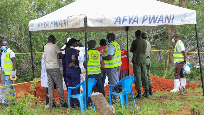 Kenyan forensic experts and homicide detectives gather under a tent.