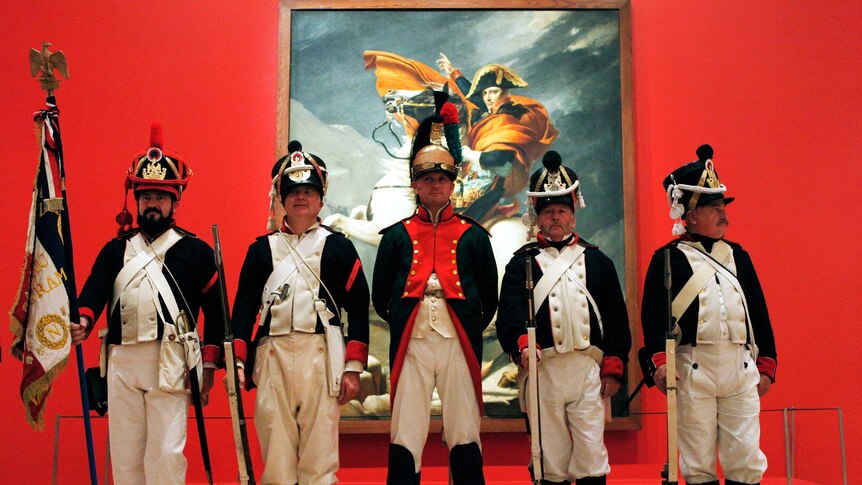 Performers in front of Napoleon portrait at exhibition preview for Napoleon: Revolution to Empire.