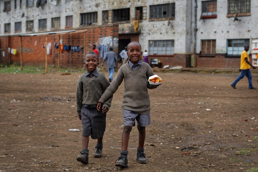 Children carry their lunches through the neighbourhood of Mbare