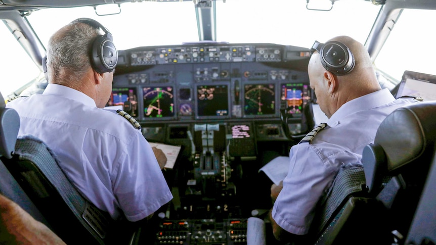 Two men in pilot's uniforms sitting in the coc
