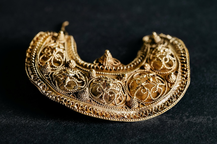 A medieval golden earring is pictured with small details on it. 