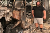 A man stands amid the rubble of a bushfire-hit property