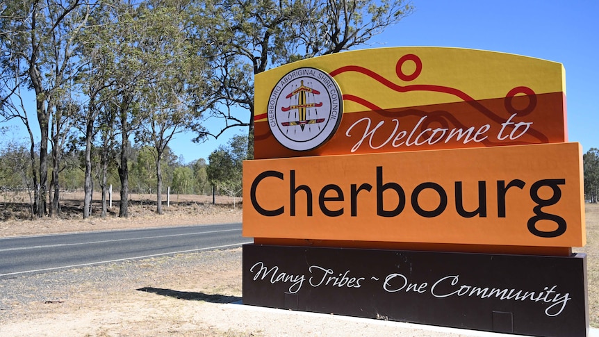 A bright orange and yellow welcome sign stands as a greeting to motorists driving into Cherbourg.