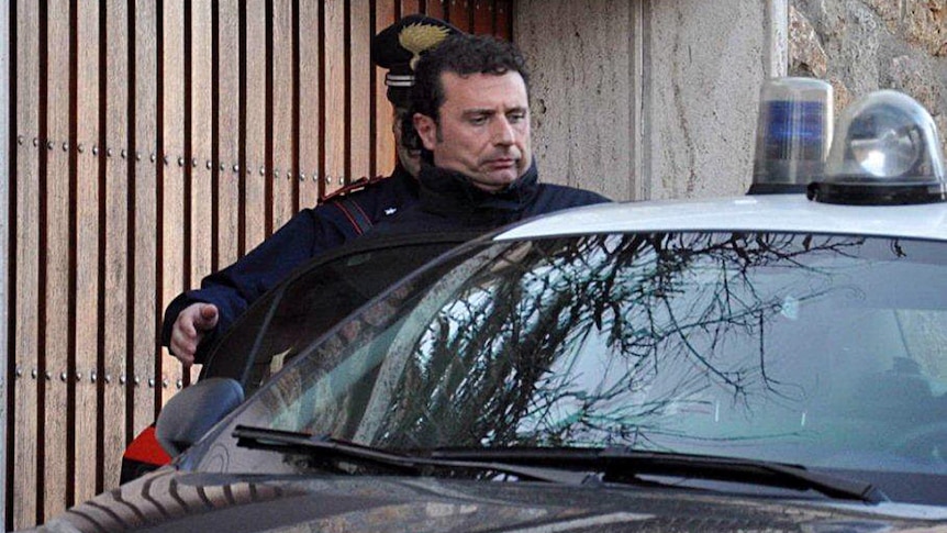 The captain of the Costa Concordia, Francesco Schettino, is escorted to an awaiting police car.