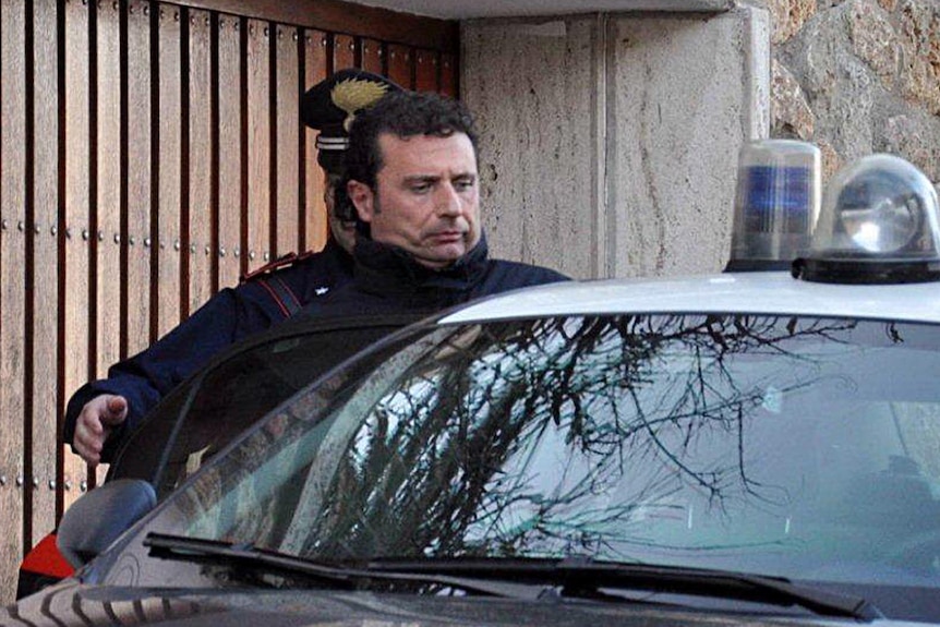 The captain of the Costa Concordia, Francesco Schettino, is escorted to an awaiting police car.