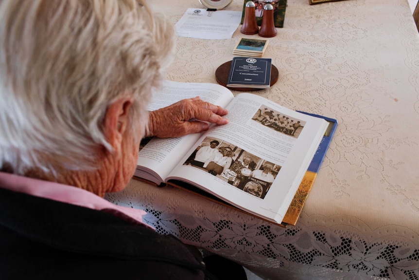 Looking over Rosie Archer's shoulder, reading a book with historical photos and her CWA constitution.