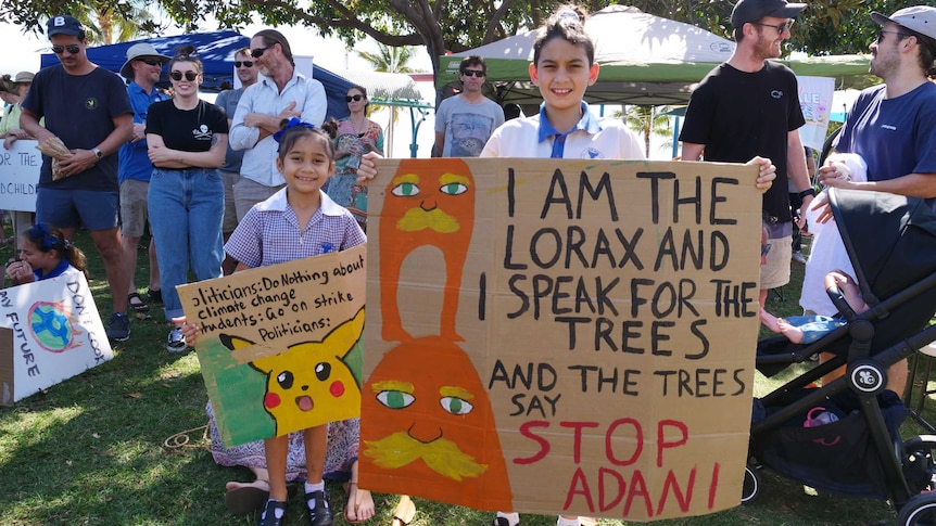 A student holds a placard reading 'I am the Lorax and I speak for the trees, and the trees say Stop Adani'.