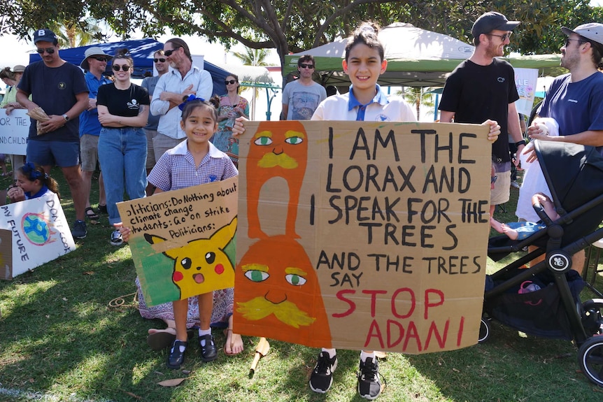 A student holds a placard reading 'I am the Lorax and I speak for the trees, and the trees say Stop Adani'.