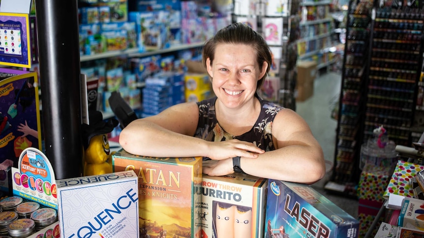 Pemilik toko permainan papan Cathy Bimrose berpose di tokonya dengan permainan untuk sebuah cerita tentang permainan papan dan kartu yang menyenangkan untuk dimainkan.