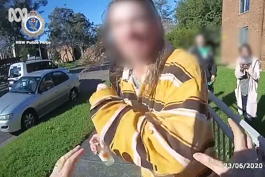 Still frame from a police body camera showing an officer's point of view of a man whose face is blurred and two onlookers
