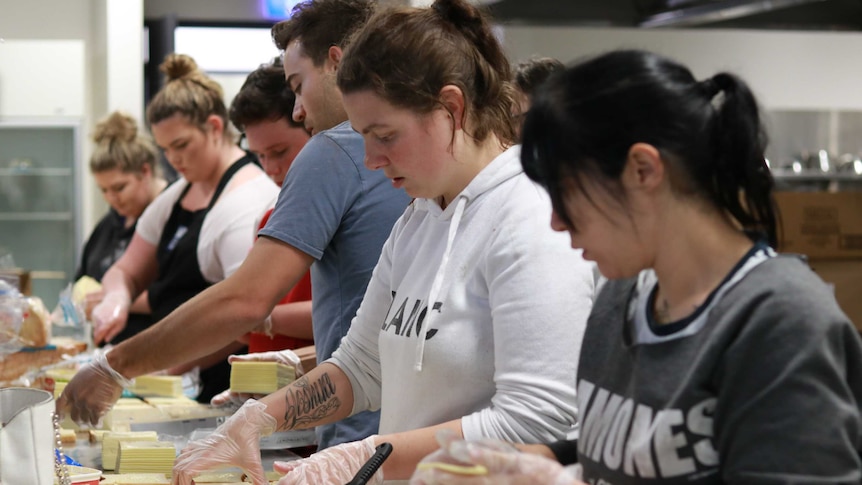 Five students prepare sandwiches in an industrial TAFE kitchen