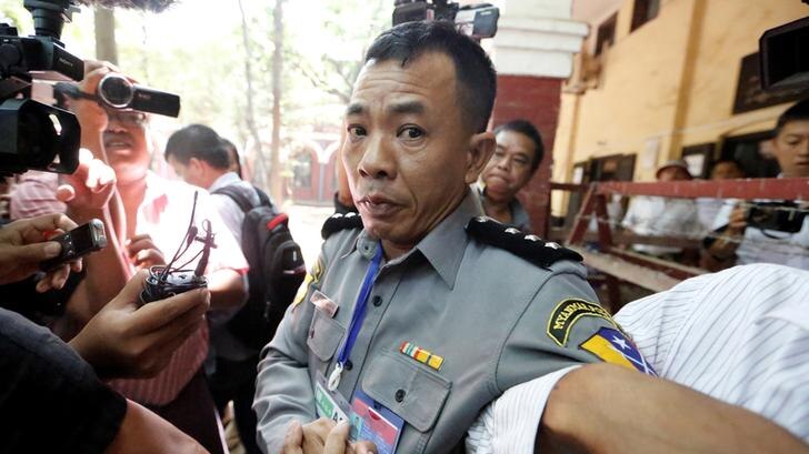 Police Captain Moe Yan Naing surrounded by reporters after he testified in court