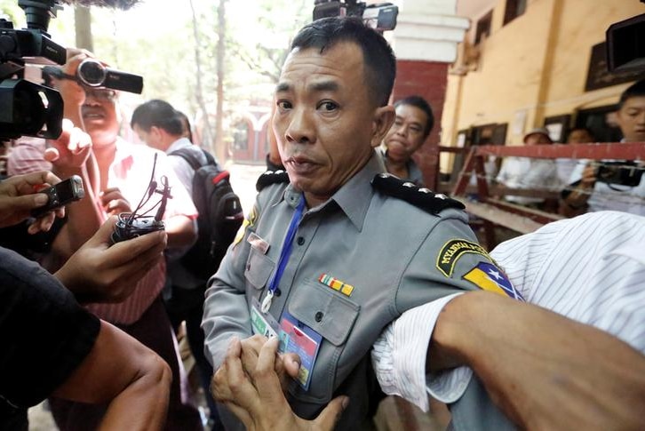 Police Captain Moe Yan Naing surrounded by reporters after he testified in court