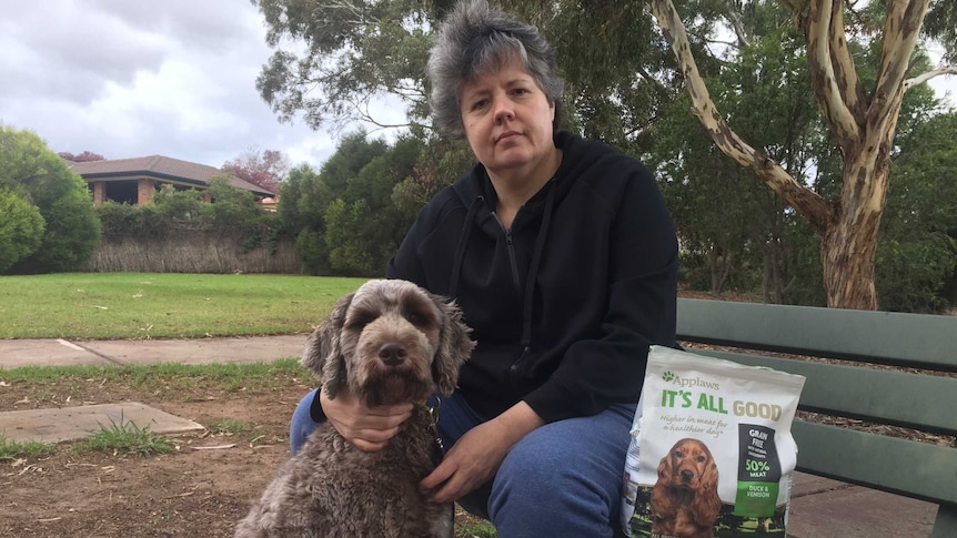 Ruth Quick sitting on a park bench with her dog, Sergio, and a packet of Applaws dog food