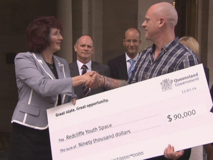 TV still of Speaker of Parliament Fiona Simpson handing ceremonial $90K cheque to Redcliffe Youth Space CEO Jarryd Williams. Wed Feb 12, 2014