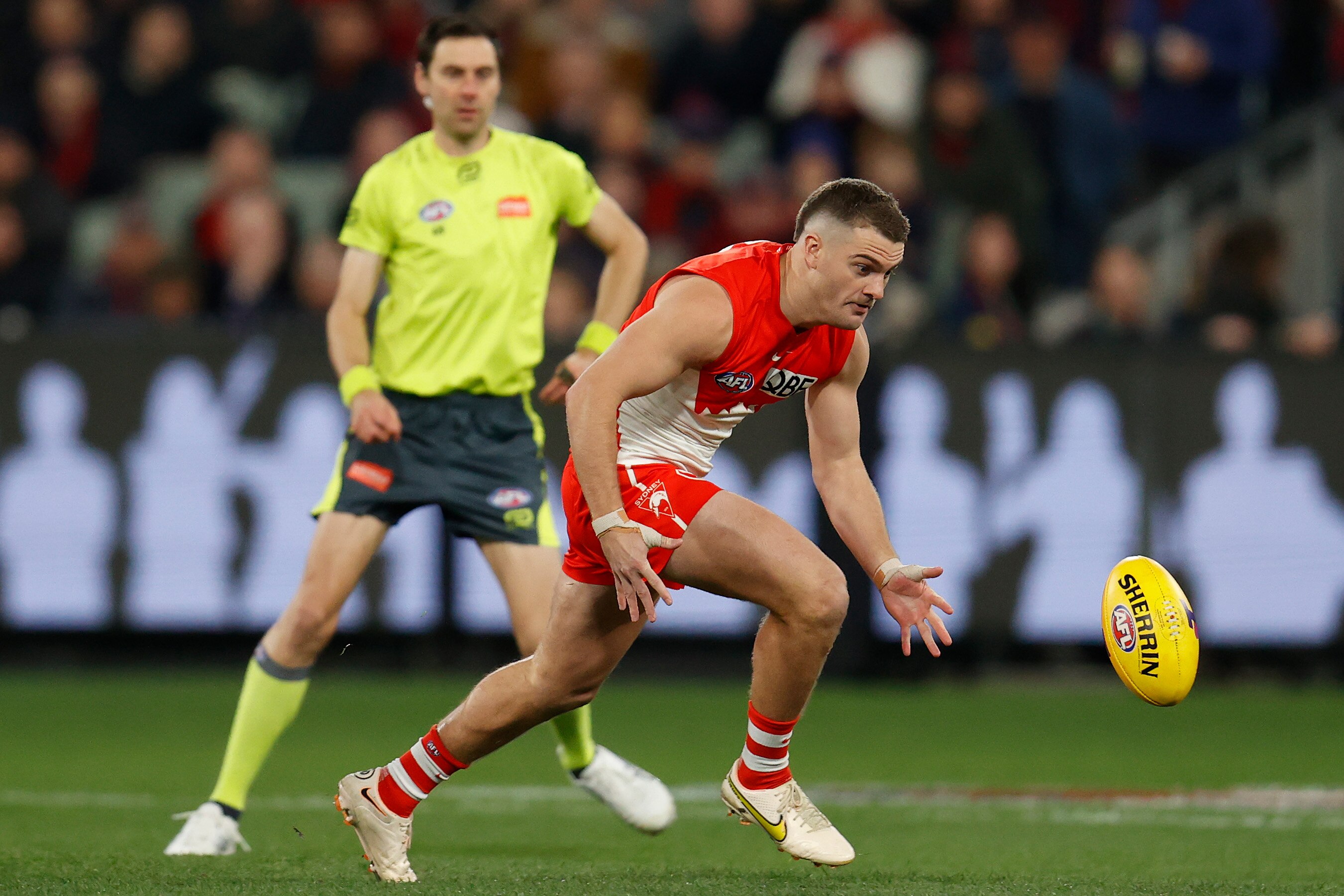 A Sydney Swans forward bends down to scoop up the ball on the run in an AFL final.