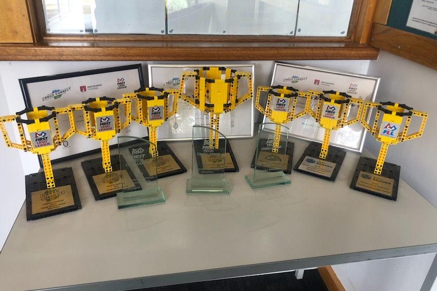A collection of Lego trophies on a wooden desk. 