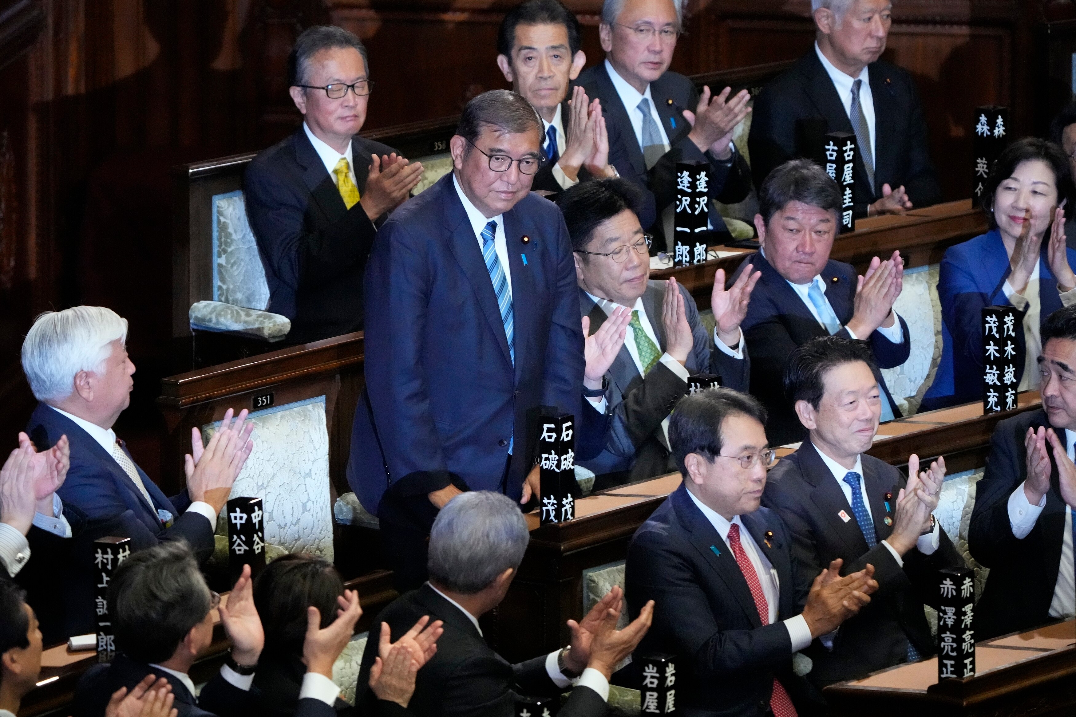Prime Minister Shigeru Ishiba stands among other lawmakers who applaud his re-election. 