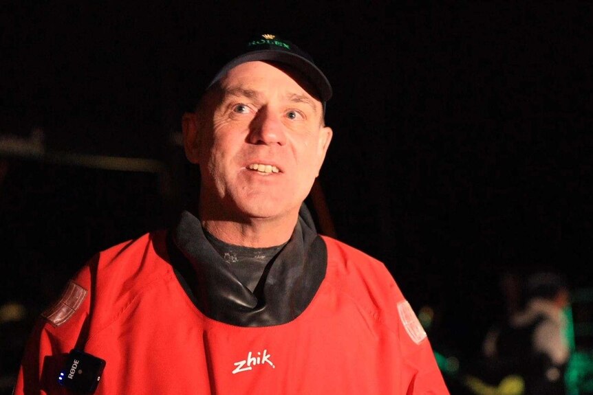 man with cap smiles after stepping off a boat in the dark