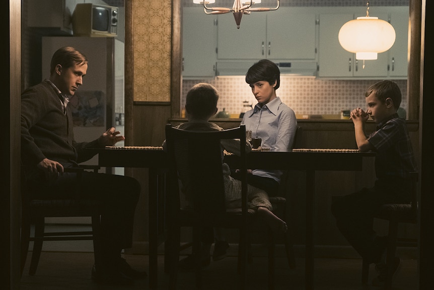 Still of Ryan Gosling, Claire Foy, Luke Winters and Conor Blodgett sitting together at a dining table in 2018 film First Man.