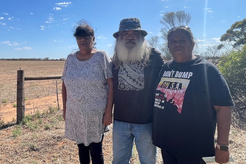 three people stand in from of an empty field