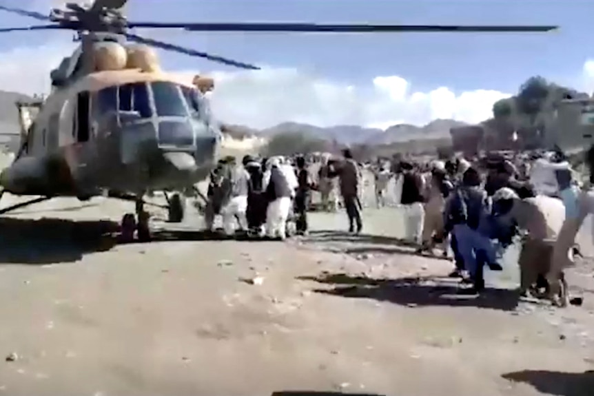 Люди несут раненых к вертолету