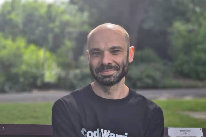 A bald man smiling wearing a black T-shirt.