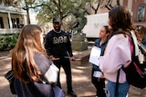African American man speaking to three college students about voting.