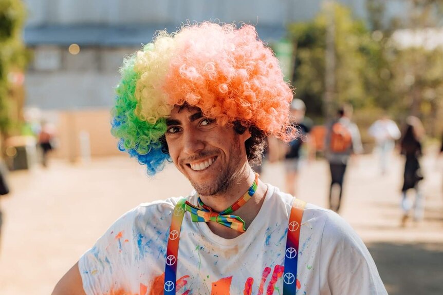 Dom Serov wears a colourful wig while attending a music festival in 2019.